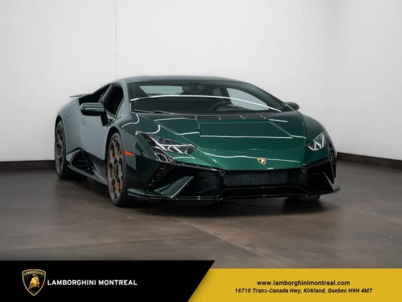 A dark green Lamborghini, one of the best supercars, is parked indoors on a polished floor next to a white wall, with dealership branding visible in the corner.