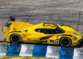 A yellow race car, emblazoned with the number 85, speeds around a track with blue and white curbs, channeling the spirit of victory reminiscent of the legendary 12 Hours Of Sebring.