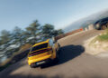 A yellow Porsche Macan Turbo Electric leads, with a dark SUV trailing behind on one of Europe's Best Driving Roads. The winding path is framed by lush trees and distant hills, offering a picturesque backdrop for an exhilarating drive.