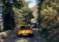 Three cars, including a yellow one in the foreground, navigate Europe's Best Driving Roads—a narrow, winding path lined with trees and mountain terrain—where a Macan Turbo Electric leads the pack.