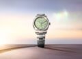 Displayed against a blurred sunset backdrop, this Rolex silver wristwatch features a striking green dial. A standout piece in the 2025 Watches collection, it embodies the elegance celebrated at Watches & Wonders.