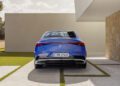 Rear view of a sleek blue Mercedes-Benz CLA parked on a paved driveway beside a modern building with stone and white walls, showcasing the elegant integration of new tech.