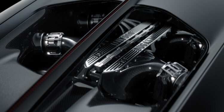 Close-up view of a Bugatti V16 engine under a clear cover, showcasing detailed mechanical components and carbon fiber surfaces—a stunning glimpse into cutting-edge automotive development.