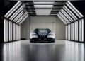 A Bugatti sports car, powered by the legendary W16 engine inspired by Ferdinand Piëch’s vision, is parked inside a well-lit, modern garage with overhead and side fluorescent lights.