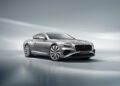 A silver Bentley Continental GT luxury coupe glistens on a reflective surface, its sleek silhouette contrasted against a beautifully blurred background.
