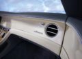 Luxurious Bentley car interior with a beige dashboard featuring "Azure" branding, a round air vent, and elegant wood panel accents.