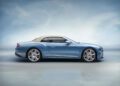 A sleek blue convertible Bentley with a beige soft top is gracefully parked on a smooth surface. Its side view is set against a gradient blue background, echoing the luxurious charm of the Continental GTC.