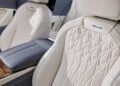 Close-up of a luxury car interior featuring white leather seats with diamond stitching, labeled "Azure," complemented by a blue leather armrest and wooden paneling. This exquisite design echoes the elegance of a Bentley Flying Spur.