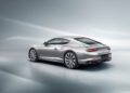 Sleek silver Bentley Continental GT on a glossy surface, viewed from the rear side, showcasing aerodynamic design and polished alloy wheels.