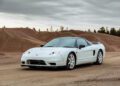 A sleek Lamborghini Diablo is parked on a dirt road, framed by sand mounds and a cloudy sky, ready for its moment at Broad Arrow Auctions.