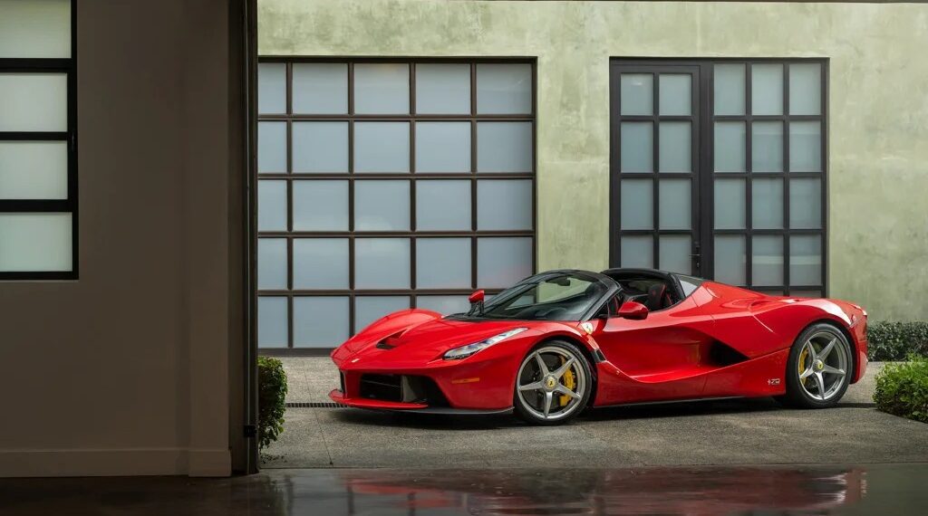 A stunning 2017 Ferrari is parked in a modern garage with floor-to-ceiling windows and sleek concrete walls, presenting an irresistible allure for car enthusiasts.