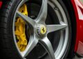 Close-up view of a Ferrari LaFerrari Aperta wheel with a five-spoke metallic rim, yellow brake caliper, and iconic Ferrari logo on the hub. The tire is black against the vibrant red car body. Perfect for enthusiasts seeking a 2017 Ferrari for sale.