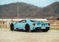 A sleek, blue Lamborghini Diablo VT 6.0 sits elegantly on a gravel area, with majestic mountains forming a stunning backdrop.