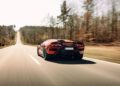A red Lamborghini Diablo VT 6.0 speeds down a rural road, flanked by bare trees and a clear sky, resembling a scene straight out of high-end auctions.