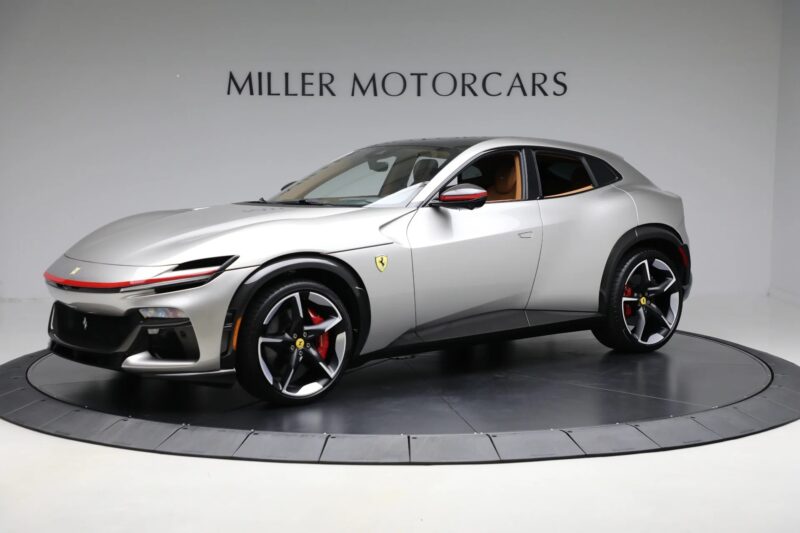A silver Ferrari Purosangue SUV is displayed in a showroom with "Miller Motorcars" signage in the background, showcasing the stunning Ferrari Purosangue for sale.