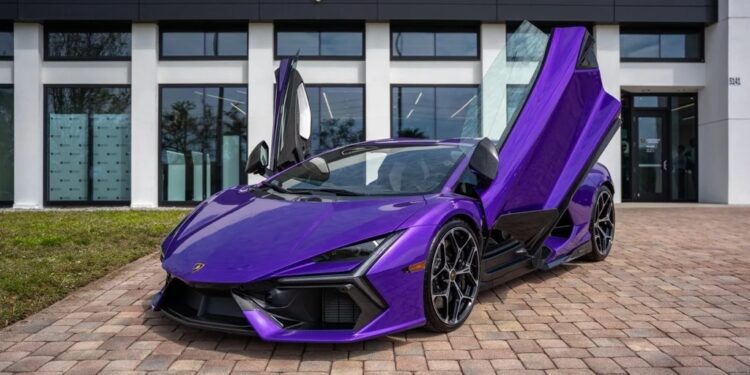 A purple Lamborghini Revuelto with its scissor doors open is parked on a brick driveway in front of a dealership, showcasing one of the best Lamborghini supercars for sale.