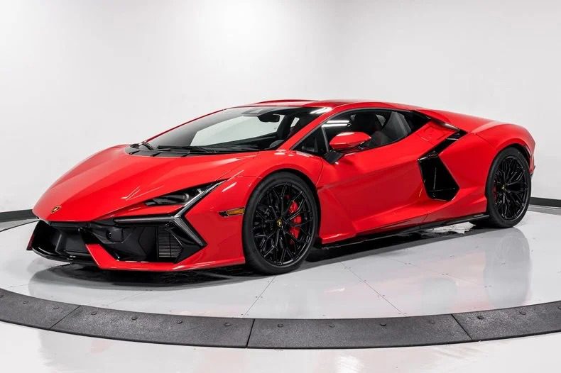 A red Lamborghini Revuelto sports car is parked in a white showroom with black accents on the wheels and body, showcasing the allure of Lamborghini for sale among other supercars for sale.