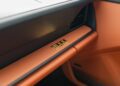 Interior of a Riviera Blue Porsche 911 featuring luxurious brown leather and a striking gold "911" emblem on the dashboard.
