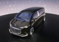 An ultra-luxury black Mercedes-Benz minivan concept with large wheels and a futuristic design is displayed on stage, set against a backdrop featuring repeating Mercedes-Benz logos.