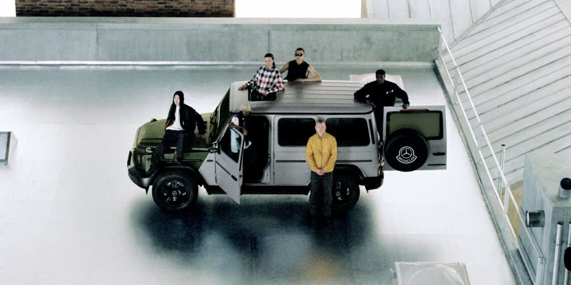 Five people gather on a rooftop with a sleek green vehicle. Some lounge atop the Mercedes-Benz, while one stands beside it. The urban backdrop of concrete and brick adds to the scene's edgy vibe, reminiscent of a stylish Moncler photoshoot.