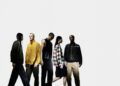 Five people stand in a line against a plain background, each wearing distinct casual and streetwear clothing inspired by NIGO’s bold aesthetics.