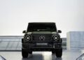 In an industrial setting, the front view of a sleek black Mercedes-Benz SUV stands boldly with a license plate that reads "PAST II FUTURE." This elegant vehicle captures the essence of timeless style and innovation, much like the designer collaborations seen with Moncler.