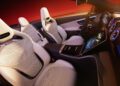 The interior of this limited-edition car features white leather seats, a touchscreen display, and a sleek dashboard. The background is a gradient of red and orange, embodying the exclusive style of the Mercedes-AMG CLE MANUFAKTUR Edition.