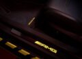 A close-up of the Mercedes-AMG interior footwell reveals yellow ambient lighting with the AMG logo elegantly displayed on the floor mat and door sill, exemplifying the exclusive touches of a CLE MANUFAKTUR Edition vehicle.