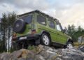 A green Mercedes-Benz G-Class 1-of-460 SUV is parked on rocky terrain with trees and greenery in the background, embodying a spirit that's STRONGER THAN THE 1980s.