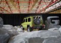 A green Mercedes-Benz G-Class 1-of-460 SUV is displayed indoors among artificial rocks, with large black curtains and a metallic "G" sculpture in the background—truly STRONGER THAN THE 1980s.