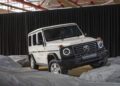 A white Mercedes-Benz G-Class SUV, 1-of-460 and STRONGER THAN THE 1980s, is displayed indoors on artificial gray rocks with a black curtain backdrop.