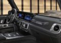 Interior view of a modern Mercedes-Benz G-Class highlighting the dashboard, digital displays, and steering wheel, with "STRONGER THAN THE 1980s" engraved on the passenger side.