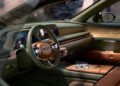 Experience the luxury of a Genesis interior, featuring green leather seats, brown accents, and elegant wood paneling. It boasts a digital dashboard, a large touchscreen, and a sleek steering wheel that redefine Convertible Concepts in automotive comfort.