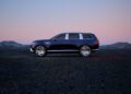 A dark SUV, the centerpiece of the Genesis Blank Canvas Campaign, is parked on a barren landscape at dusk with majestic mountains in the background.