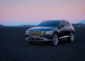 A black Genesis SUV is parked on a dark gravel landscape at twilight, with a mountain range visible in the background under a pinkish sky, embodying the essence of the Blank Canvas Campaign.