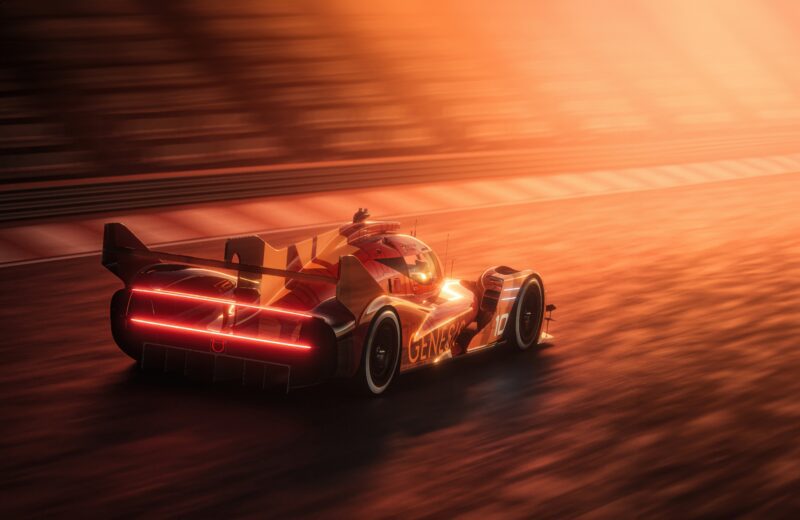 A GMR-001 Hypercar with red taillights illuminated speeds along a racetrack at sunset, its silhouette reminiscent of the Genesis debut at the New York International Auto Show, with blurred stands in the background.