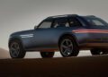 A modern blue Genesis X Gran Equator SUV with illuminated horizontal light bars is parked on sand dunes under soft lighting, showcasing Genesis unveils a bold off-road concept.