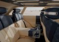 The image shows the rear interior of the Genesis X Gran Equator Off-Road Concept, featuring beige and black quilted leather seats, fold-out trays, and large windows, all set against a striking desert landscape.