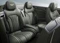 Luxurious car interior featuring green leather seats with detailed stitching, branded headrests, and a sleek center console, reminiscent of the opulent cabin found in a Bentley Continental GT.