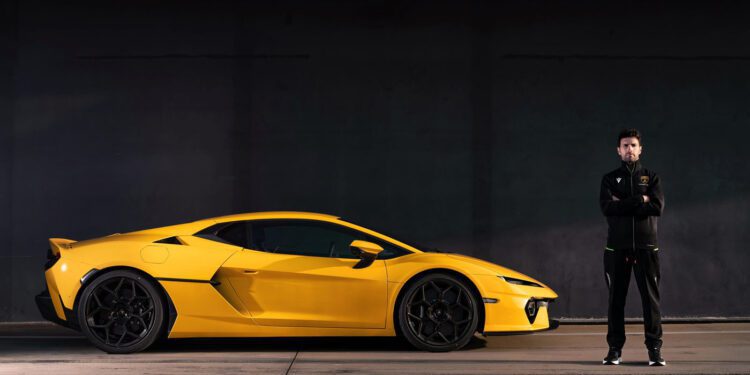 A person stands next to a sleek Lamborghini sports car in a dimly lit setting, exuding the aura of a factory driver ready to push limits.