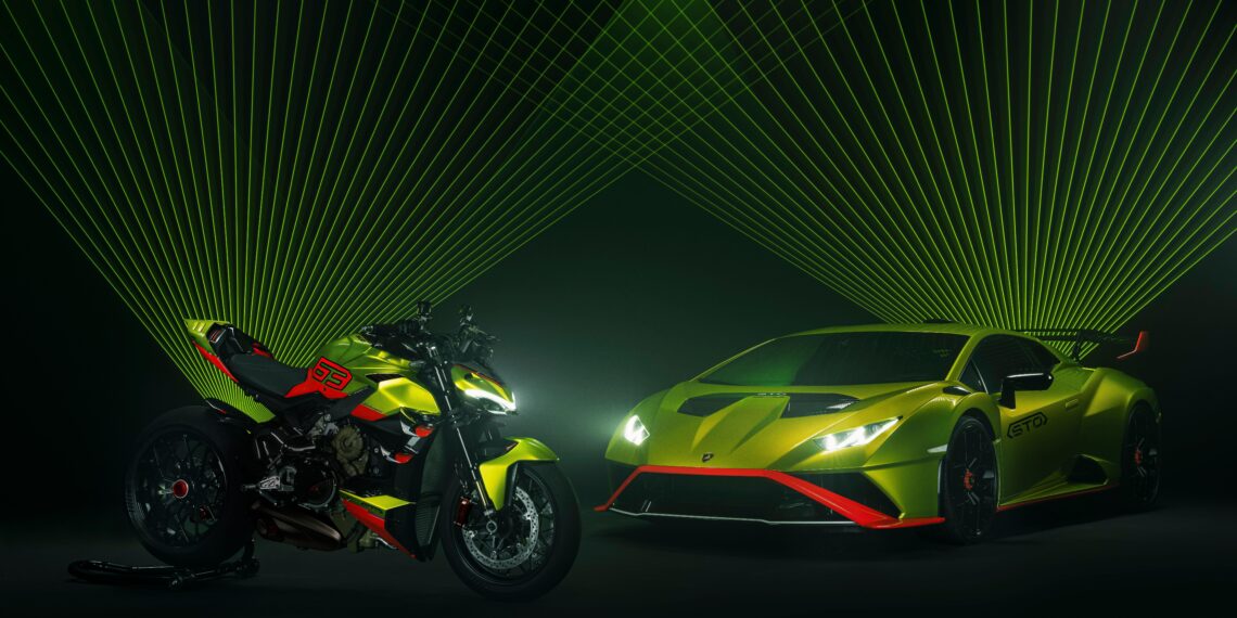 A neon green Lamborghini and Ducati motorcycle are parked side by side under green laser lights, creating a dynamic visual effect reminiscent of the vibrant displays at Milan Design Week.