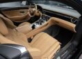 The interior of a luxury car featuring tan leather seats, detailed stitching, a modern dashboard, and sleek metallic controls.