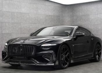 A black Bentley Continental GT with striking Mansory customizations is parked in a modern, gray-tiled showroom with soft, indirect lighting.