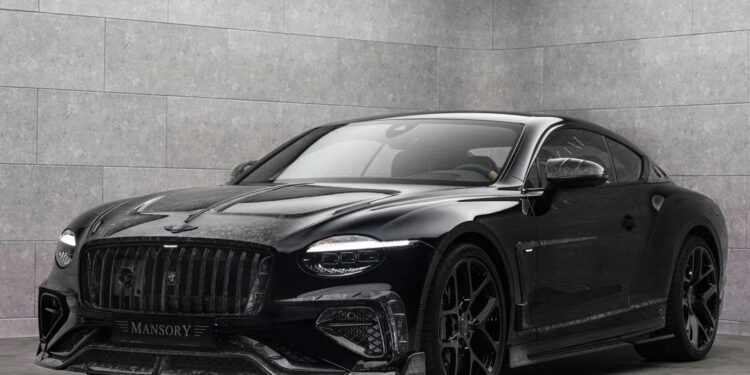 A black Bentley Continental GT with striking Mansory customizations is parked in a modern, gray-tiled showroom with soft, indirect lighting.