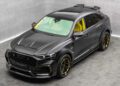 A matte black Audi SUV with yellow interior accents and detailing is parked in a minimalist, gray-walled showroom.