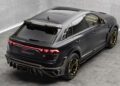 A matte black Audi RS Q8 with Mansory customizations, yellow accents, and custom wheels is parked in a concrete-walled indoor space.