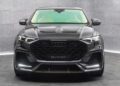 Front view of a black Audi RS Q8 SUV with Mansory customizations, parked in a gray, modern, indoor showroom.