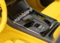 Close-up of a car's black center console with yellow accents, showcasing customizations like the gear selector, control buttons, and "Mansory Atelier" branding—perfectly suited for an Audi RS Q8.