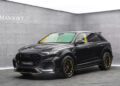 A black, facelifted Audi RS Q8 with Mansory customizations is parked indoors on a gray floor, featuring yellow accents and striking sporty body modifications.