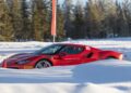 A red Ferrari sports car with "Corso Pilota" and "10" markings glides through a snowy landscape, trees standing tall in the background.